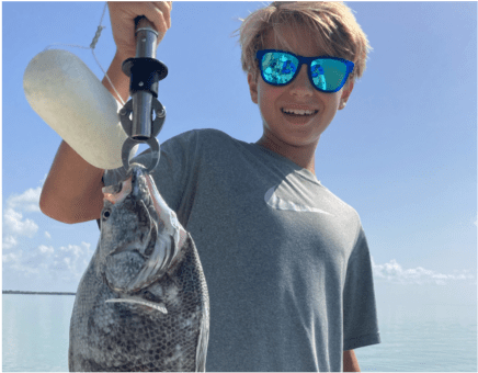Male teenager holding a Tripletail fish