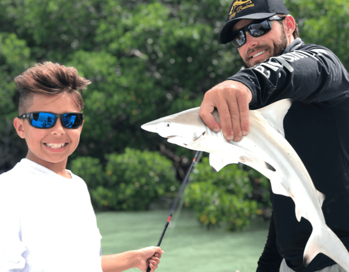 Captain Drew with male child posing with small shark